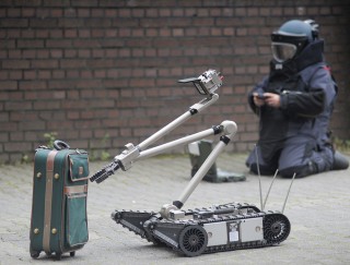 Einsatzkräfte der Polizei entschärfen eine Kofferbombe.